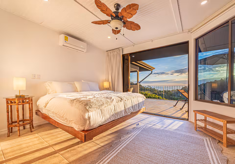 Master bedroom with king bed and sliding glass doors opening to an ocean view at KsaLinda villa, Costa Rica